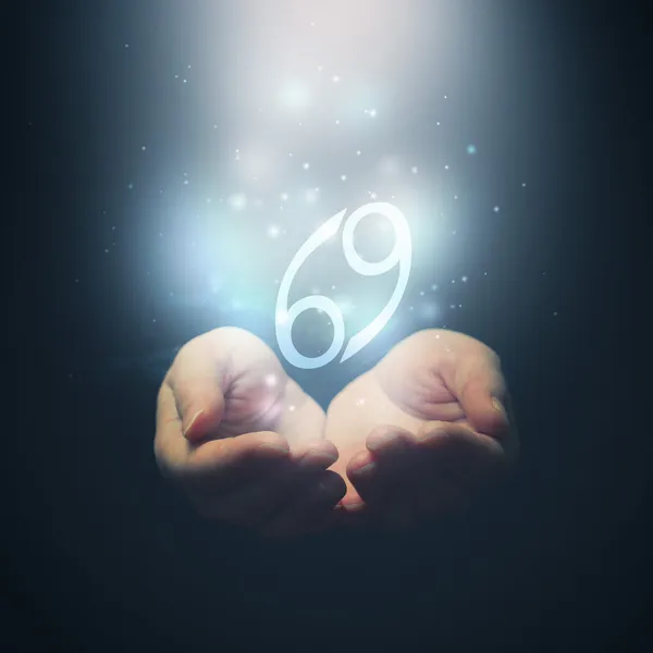 Female hands opening to light and holding zodiac sign for Cancer — Stock Photo, Image