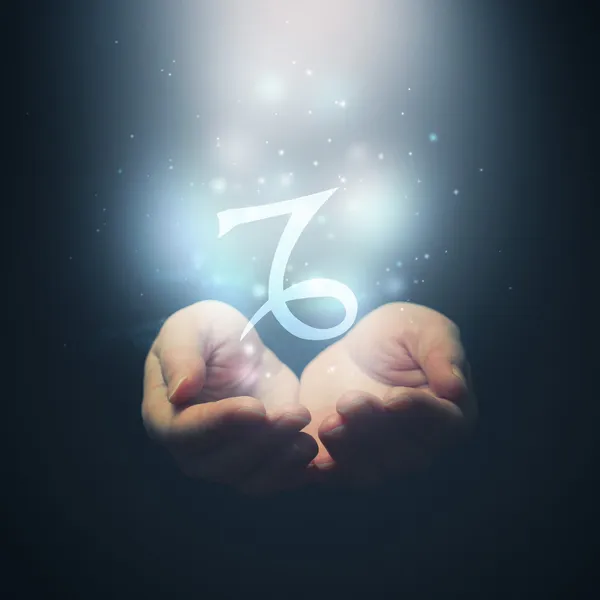 Female hands opening to light and holding zodiac sign for Capricorn — Stock Photo, Image