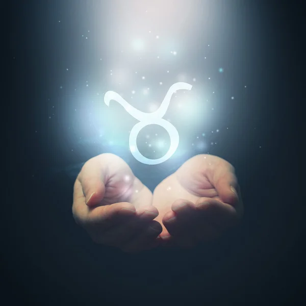 Manos femeninas abriéndose a la luz y sosteniendo el signo del zodíaco para Tauro — Foto de Stock