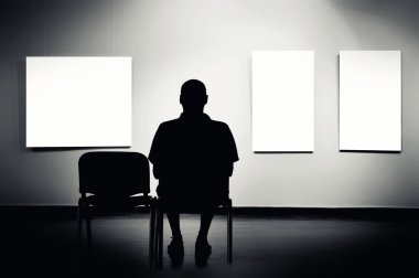Sanat galerisinde oturan adam