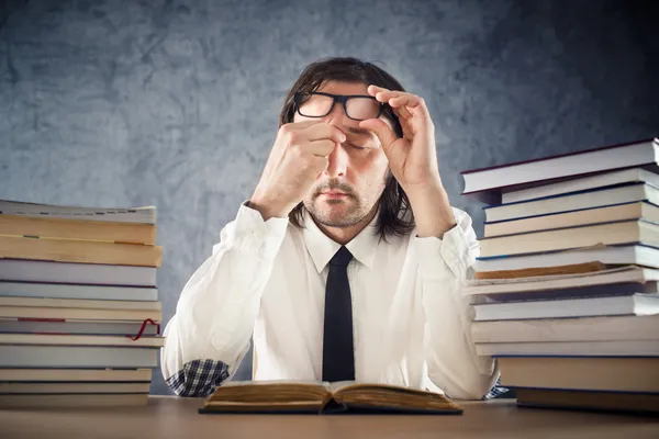 Exhausted man reading books — Stock Photo, Image