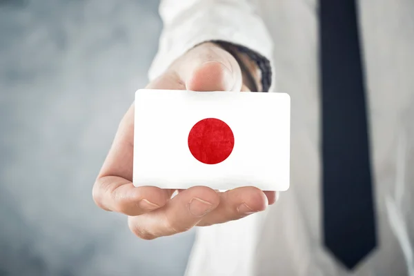 Empresário japonês segurando cartão de visita com bandeira do Japão — Fotografia de Stock