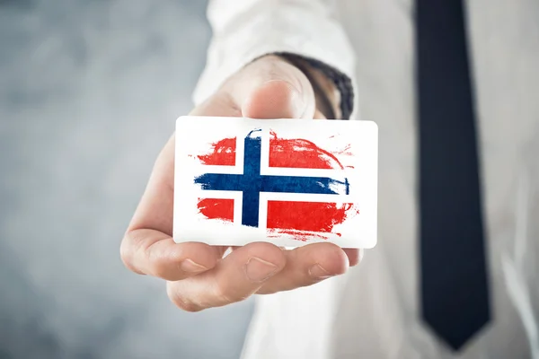 Норвежский бизнесмен с визитной карточкой под флагом Норвегии — стоковое фото