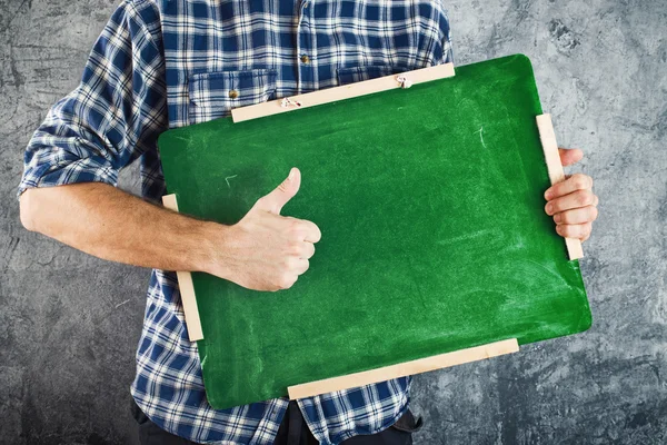 Man bedrijf groene schoolbord en duim opdagen — Stockfoto