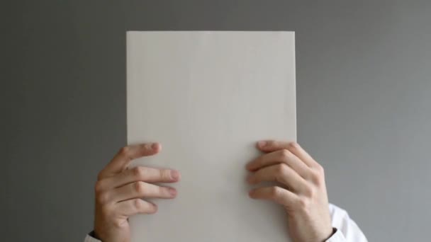 Businessman holding blank paper in front of his face with copy space for business message — Stock Video