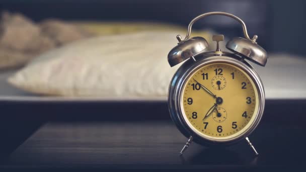 Reloj despertador vintage en el dormitorio en una mesa de noche junto a la cama . — Vídeos de Stock