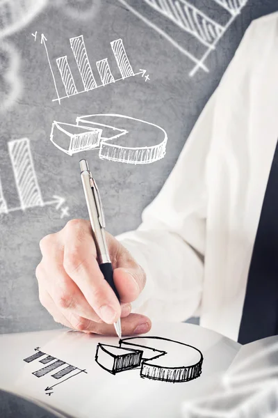 Businessman drawing pie chart and other infographics in note pad — Stock Photo, Image