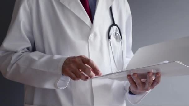 Male doctor is reading prescription while standing. Health care professional writing. — Stock Video