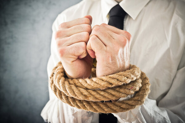 Businessman with hands tied in ropes