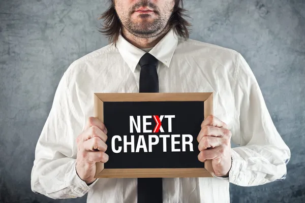 Businessman holding blackboard with NEXT CHAPTER title — Stock Photo, Image