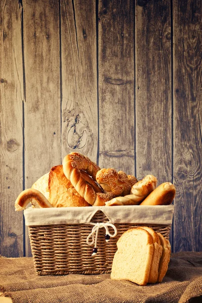 Delicious bread and rolls inwicker basket — Stock Photo, Image