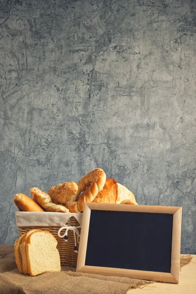 Delicious bread and rolls in wicker basket — Stock Photo, Image