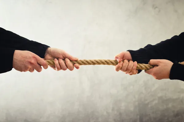 Tug of war. Hands pulling rope to opposite sides — Stock Photo, Image