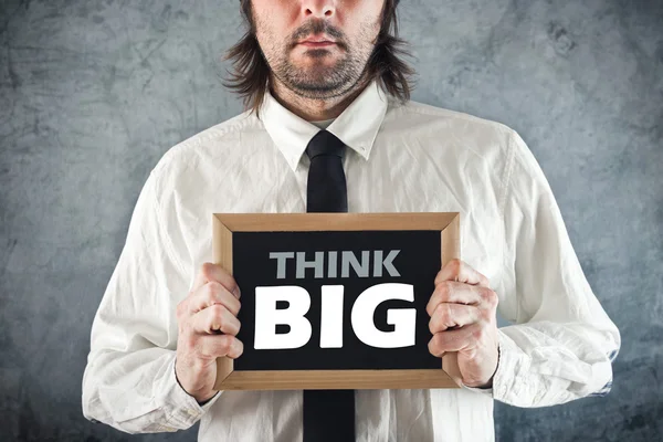 Empresario sosteniendo pizarra con título THINK BIG — Foto de Stock