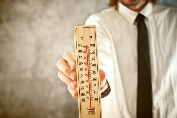 Geschäftsmann hält Thermometer in der Hand, um hohe Temperaturen zu messen — Stockfoto
