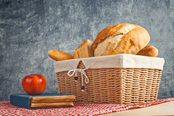Delicious bread and rolls in wicker basket — Stock Photo, Image