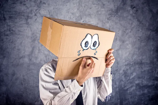 Geschäftsmann mit Karton auf dem Kopf und traurigem Gesichtsausdruck — Stockfoto