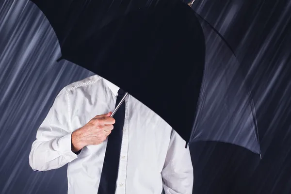 Empresário com guarda-chuva preto protegendo da chuva — Fotografia de Stock