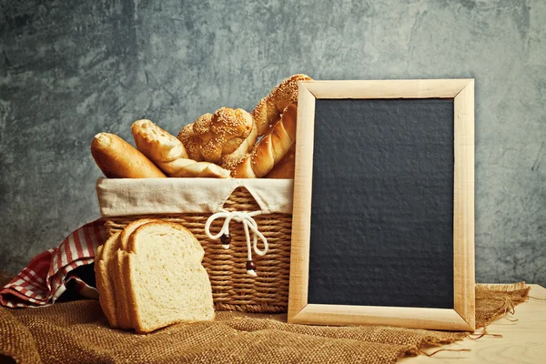 Delicious bread and rolls in wicker basket — Stock Photo, Image