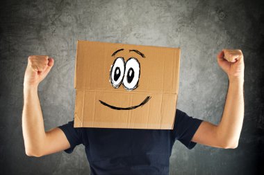 karton kutu üzerinde kafa ve yükseltilmiş yumruğu ile mutlu gülen adam