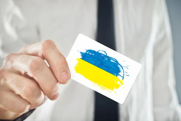 Homme d'affaires ukrainien tenant une carte de visite avec le drapeau de l'Ukraine — Photo