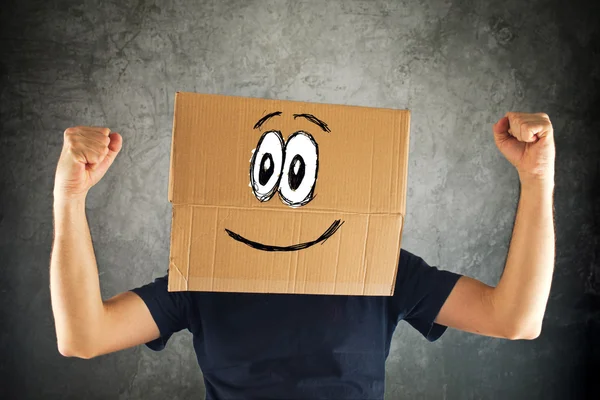 Feliz homem sorridente com caixa de papelão na cabeça e punho levantado — Fotografia de Stock