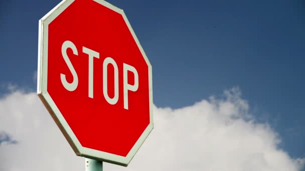 Red stop sign on the street. Roadside traffic sign for stopping with clouds time lapse footage in background. — Stock Video