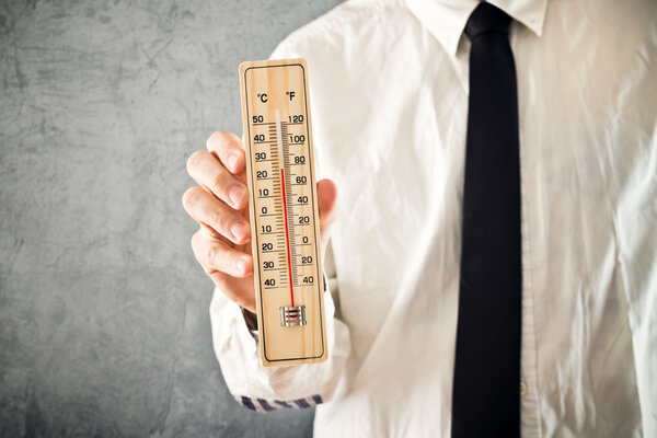 Бизнесмен держит термометр
