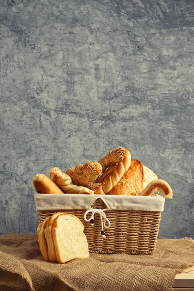 Pão delicioso e rolos em cesta de vime — Fotografia de Stock