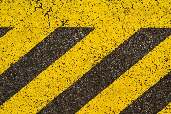 Gelb gestreifte Fahrbahnmarkierungen auf schwarzem Asphalt. — Stockfoto