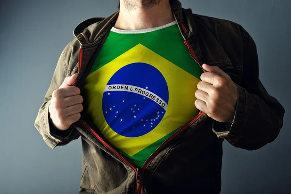 Мужчина растягивает куртку, чтобы показать рубашку с флагом Бразилии — стоковое фото