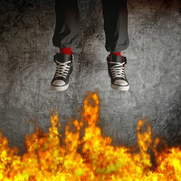 Молодой человек в кроссовках прыгает через огонь — стоковое фото