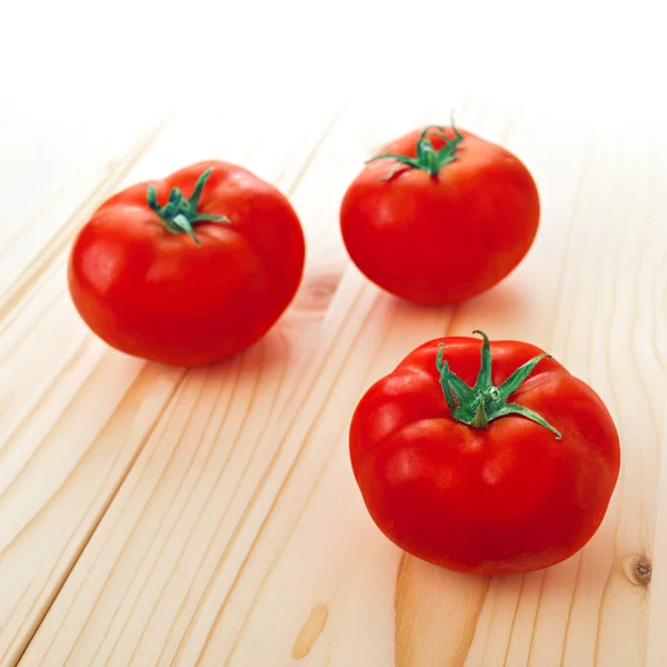 Three Fresh ripe tomatoes on wood table — Stock Photo, Image