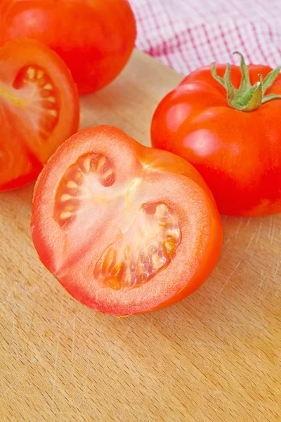 Tomates fraîches mûres avec moitiés sur table en bois — Photo