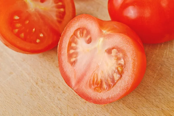 Färska mogna tomater med halfs på bord av trä — Stockfoto