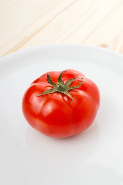 Tomate fresco maduro servido em placa branca na mesa de cozinha de madeira — Fotografia de Stock