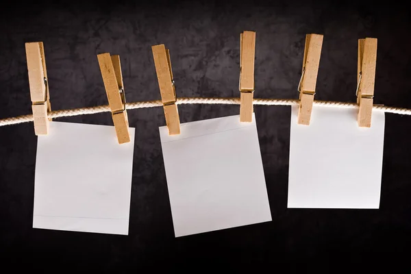 Três notas de papel em branco penduradas na corda com pinos de roupas — Fotografia de Stock