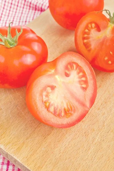 Tomates maduros frescos com metades na mesa de madeira — Fotografia de Stock