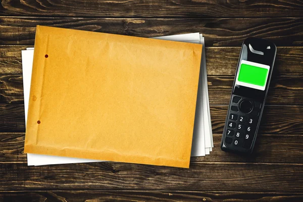 Telefone sem fio e envelope em branco na mesa — Fotografia de Stock