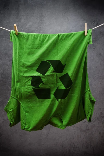 Grünes T-Shirt mit Recycling-Symbol, das zum Trocknen an einem Seil hängt — Stockfoto