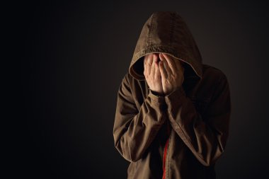 Depressive man in hooded jacket is crying 