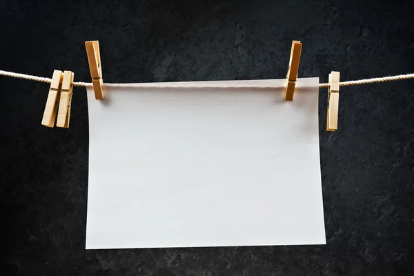 Papel de nota en blanco colgado de una cuerda con alfileres de ropa —  Fotos de Stock