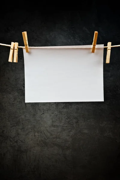 Papel de nota en blanco colgado de una cuerda con alfileres de ropa —  Fotos de Stock