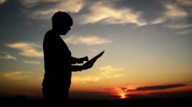 Internet tarama için dijital tablet bilgisayar kullanan kadın. kadın silueti modern gadget ayakta Günbatımı ile. 1920 x 1080 full hd ayak.
