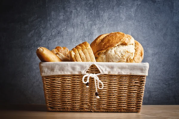 Pão delicioso e rolos em cesta de vime — Fotografia de Stock