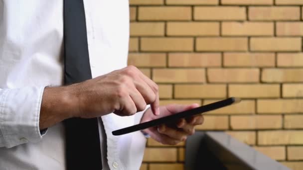 Uomo d'affari che tiene computer tablet digitale, in piedi sul balcone dell'ufficio con muro di mattoni gialli. 1920x1080 riprese hd completo . — Video Stock