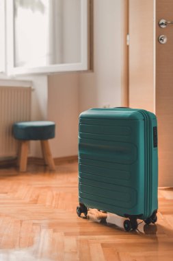 Seyahat çantası otel odasının açık kapısının arkasında, seçici bir odak noktası.