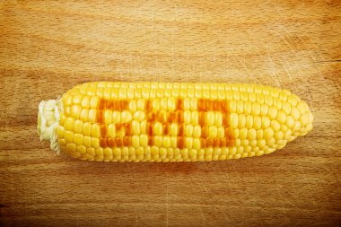 GMO Corn Maize Cob on wooden background clipart