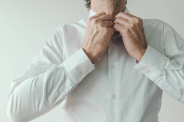 İş adamı giyiniyor, iş adamı beyaz gömleğinin düğmelerini ilikliyor, seçici bir dikkatle kapatıyor.