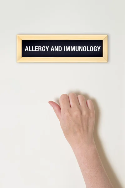 Женская рука стучится в дверь аллергии и иммунологии — стоковое фото